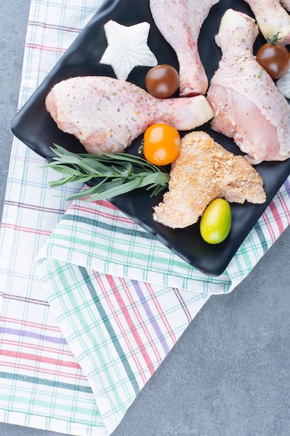 Photo gratuite préparation pour le dîner avec assiette de cuisses de poulet crues.