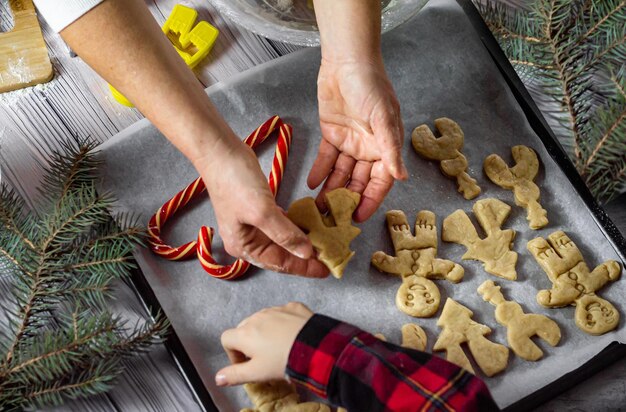 Préparation pour noël cuire les mains de femme de pain d'épice tiennent des biscuits d'arbre de noël et des mains d'enfant