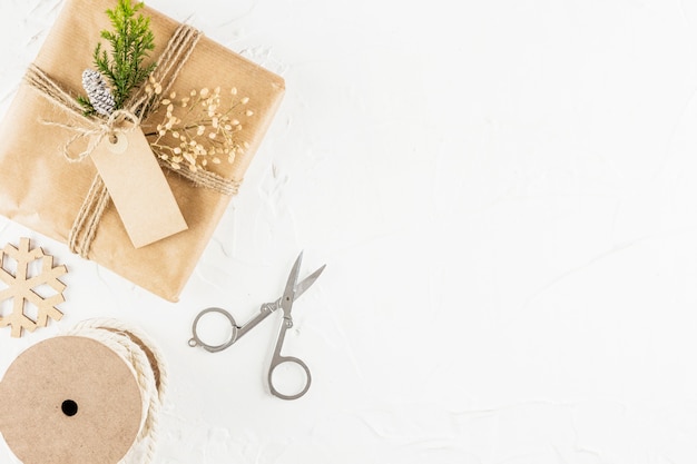 Présent dans du papier kraft avec une étiquette près des ciseaux et une canette de fils