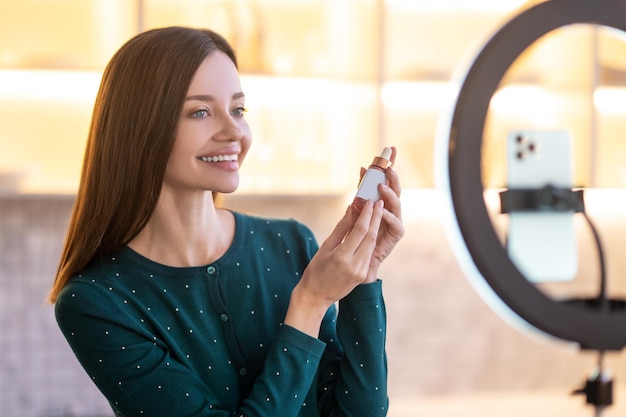 Présentation en ligne. Jeune femme représentant une nouvelle crème faciale et semblant impliquée