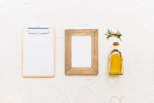 Presse-papiers et cadre en bois avec une bouteille d&#39;huile et de l&#39;herbe de romarin