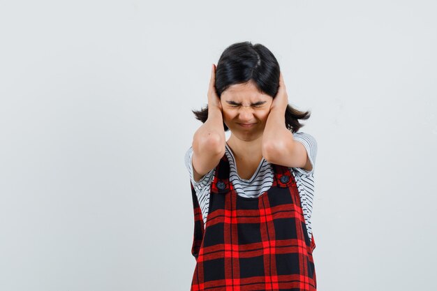 Preteen girl étreignant la tête avec les mains en t-shirt