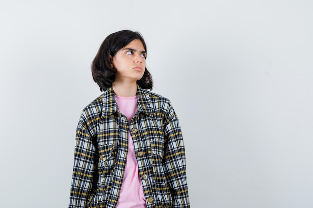 Preteen girl in shirt,veste regardant de côté, vue de face.