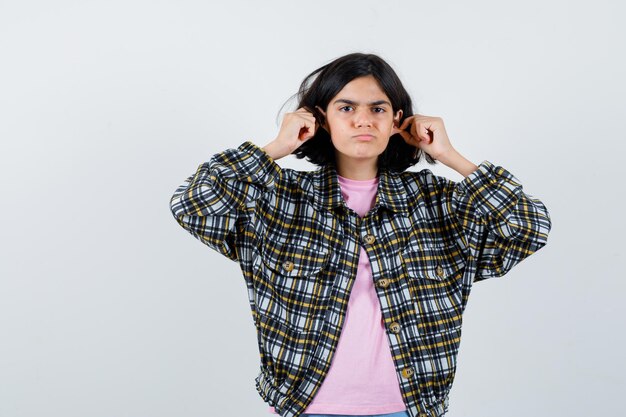 Preteen girl pinçant ses oreilles en chemise, vue de face de la veste.
