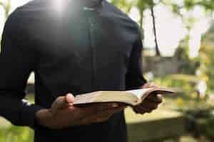 Photo gratuite prêtre masculin lisant de la bible à la tombe avec la famille de deuil