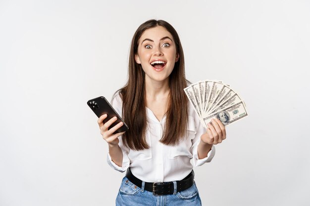 Prêts de microcrédit en ligne et concept bancaire femme heureuse tenant un téléphone portable et de l'argent souriant et ...