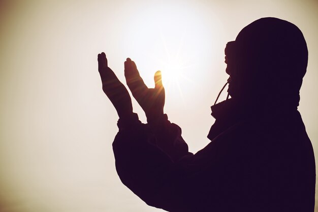 Prière spirituelle mains sur le soleil brille avec beau coucher de soleil floue