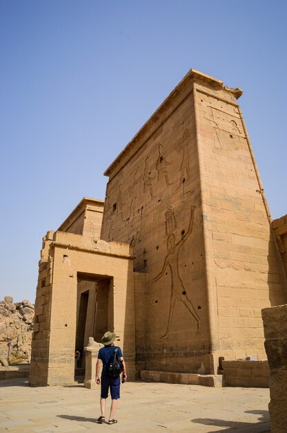Prise de vue en contre-plongée d'un homme debout devant le temple d'Isis Assouan en Egypte