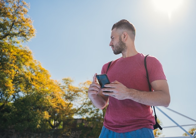 Prise de vue en contre-plongée d'un jeune homme vérifiant son téléphone avant la formation