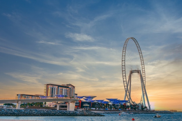 Photo gratuite prise de vue à faible angle de conception moderne d'un bâtiment avec une énorme grande roue à l'île bluewaters à dubaï