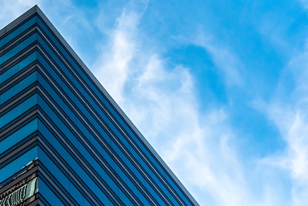 Prise de vue à faible angle de grands bâtiments en verre sous un ciel bleu nuageux