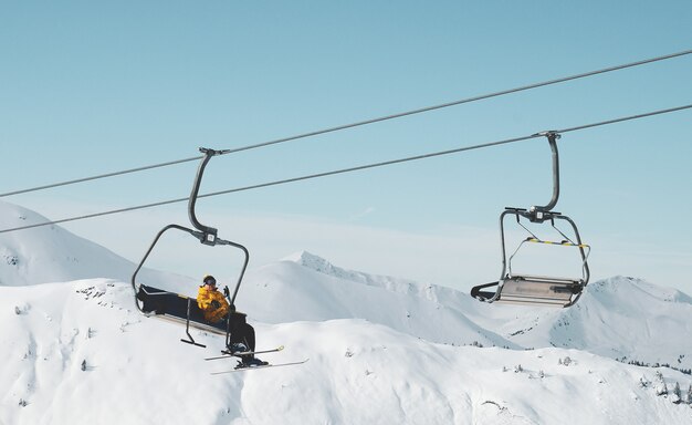 Prise de vue en faible angle d'une personne assise sur un téléphérique dans une montagne enneigée