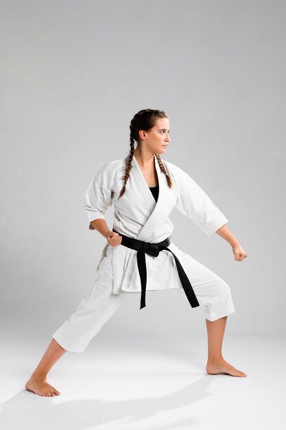 Prise de vue d'une femme à la ceinture noire et kimono pratiquant le karaté