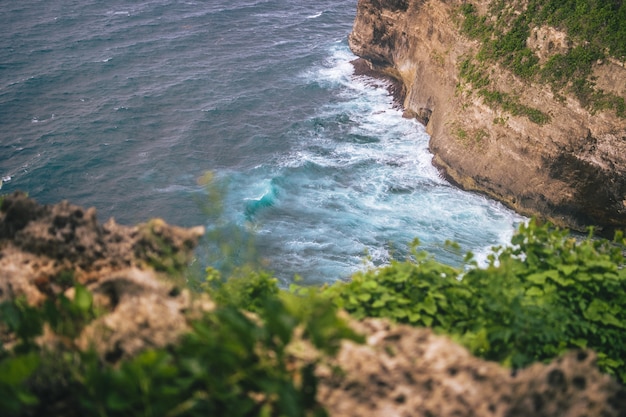 Prise de vue en grand angle de la base d'une falaise d'Uluwatu avec des vagues qui s'écrasent