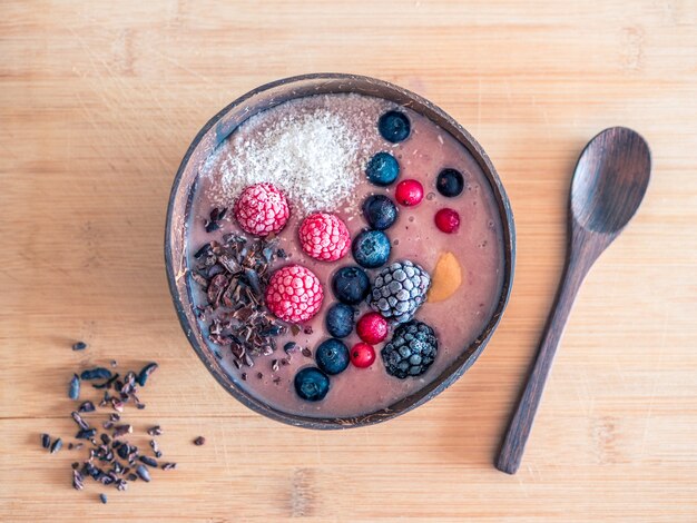 Prise de vue en grand angle d'un bol de muesli aux fruits rouges sur une surface en bois