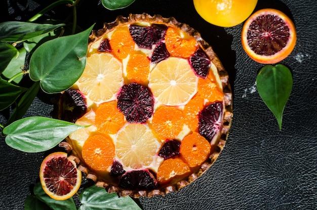 Prise de vue en grand angle d'une délicieuse tarte à l'orange fraîchement cuite sur une surface noire