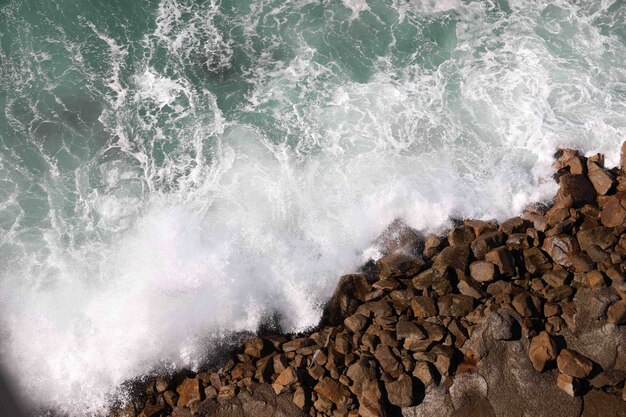 Prise de vue en grand angle d'eau éclaboussant sur les rochers de la plage