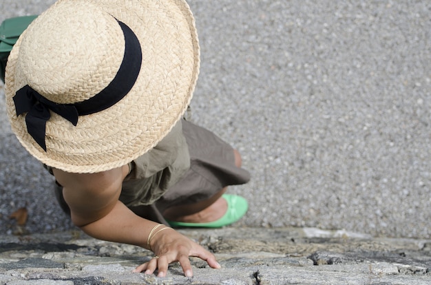 Prise de vue en grand angle d'une femme avec chapeau de paille et chaussures vertes s'appuyant sur le mur