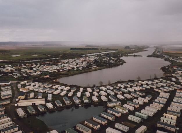 Prise de vue en grand angle des maisons rectangulaires sur les champs par un bel étang brumeux