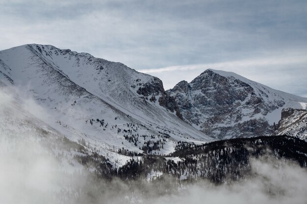 Prise de vue en grand angle des montagnes couvertes de neige sous le ciel nuageux