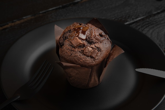 Prise de vue en grand angle d'un muffin au chocolat sur une plaque noire sur une table en bois foncé