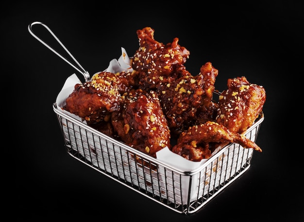 Prise de vue en grand angle d'un panier de délicieux poulet frit avec sauce piquante sur une surface noire