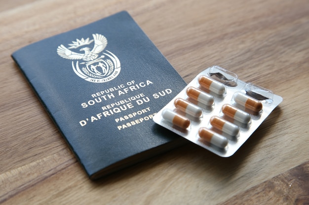 Prise de vue en grand angle d'un paquet de capsules et d'un passeport sur une surface en bois