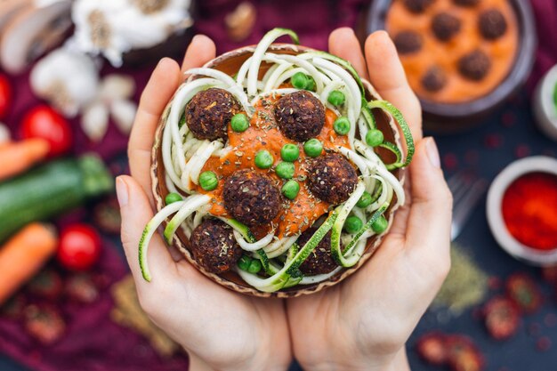 Prise de vue en grand angle d'une personne tenant un bol de délicieuses boulettes de viande de légumes