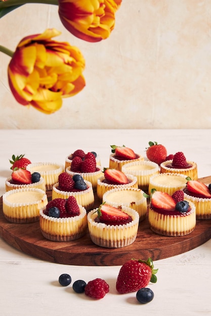 Prise de vue en grand angle de petits gâteaux au fromage avec de la gelée de fruits et des fruits sur une plaque en bois