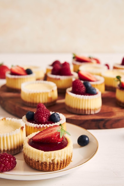 Prise de vue en grand angle de petits gâteaux au fromage avec de la gelée de fruits et des fruits sur une plaque en bois