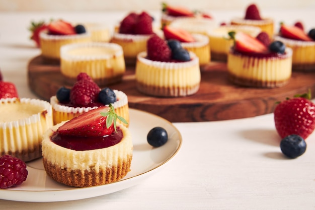 Prise de vue en grand angle de petits gâteaux au fromage avec de la gelée de fruits et des fruits sur une plaque en bois