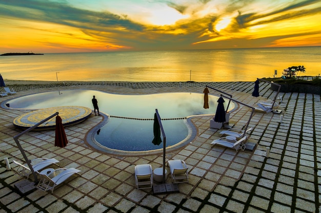 Photo gratuite prise de vue grand angle d'une piscine privée avec un océan en arrière-plan pendant l'heure du coucher du soleil