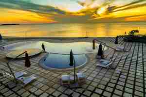 Photo gratuite prise de vue grand angle d'une piscine privée avec un océan en arrière-plan pendant l'heure du coucher du soleil