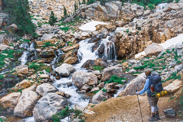 Prise de vue en grand angle d'un randonneur admirant le petit ruisseau sur les pierres