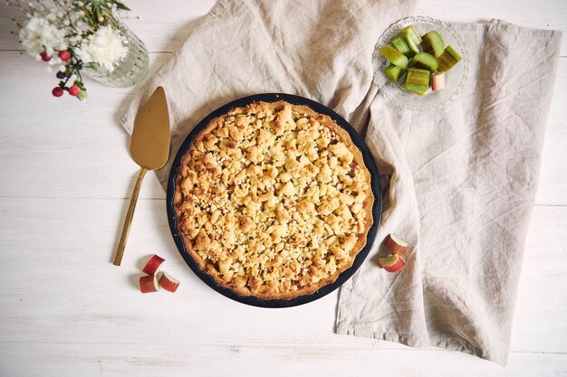 Prise de vue en grand angle d'une tarte croustillante gâteau Rhabarbar et quelques ingrédients sur un tableau blanc