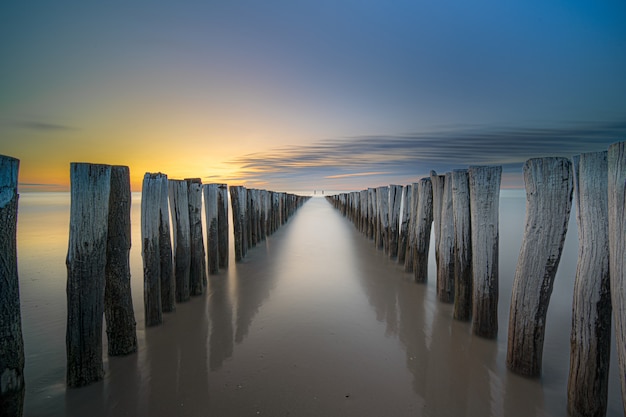 Prise de vue en grand angle d'une terrasse en bois sur le bord de mer menant à la mer au coucher du soleil