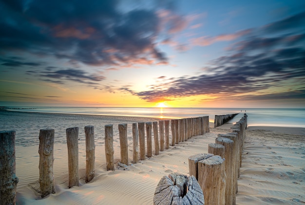 Prise de vue en grand angle d'une terrasse en bois sur le bord de mer menant à la mer au coucher du soleil