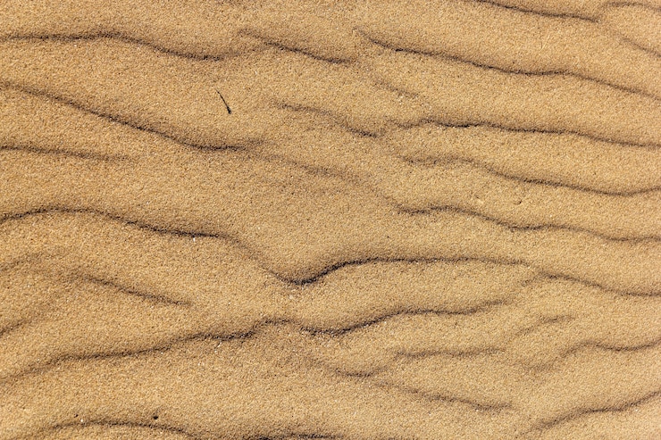 Photo gratuit prise de vue en grand angle d'une texture de sable de plage d'or rugueux