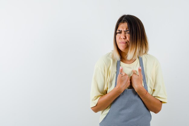 Prise de vue en studio d'une femme mexicaine triste en t-shirt jaune clair et tablier à carreaux se montre tristement isolée sur fond blanc