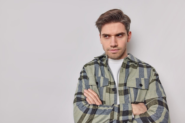 Prise de vue en studio d'un homme en colère mécontent garde les bras croisés concentrés avec une expression boudeuse porte une chemise à carreaux décontractée isolée sur fond blanc espace vide pour votre information.