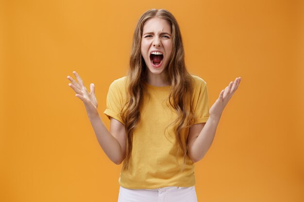 Prise de vue en studio d'une jeune femme pendant une dispute perdant son sang-froid debout sous la pression et énervée en criant l...