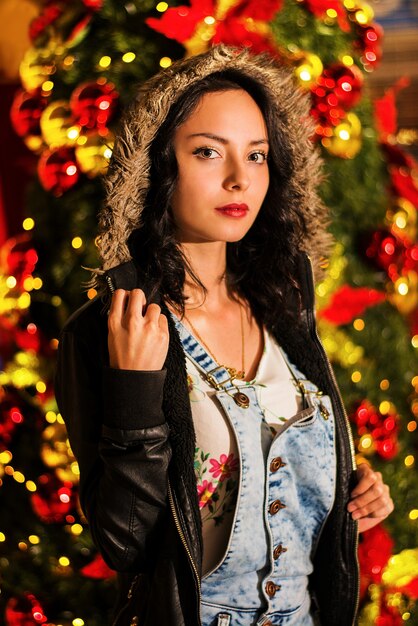 Prise de vue verticale d'une belle jeune femme devant un arbre de Noël