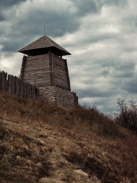 Prise de vue verticale à faible angle d'une construction en bois près d'une clôture sous un ciel nuageux