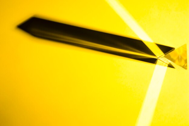 Prisme de cristal avec une ombre portée sur un fond jaune