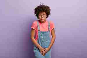 Photo gratuite problème médical, concept d'incontinence. une femme afro-américaine mécontente hods entrejambe, attend près de toilettes fermées, a besoin de toilettes