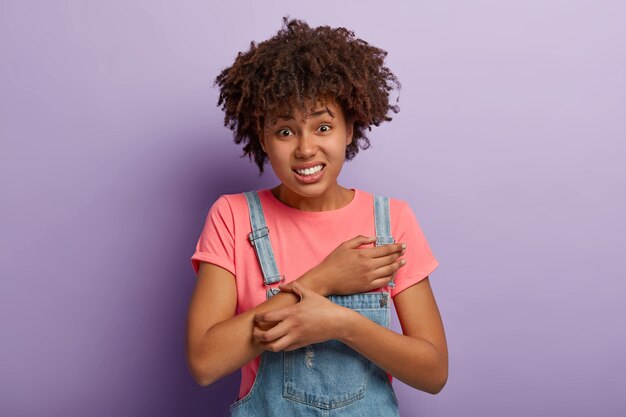 Problème de peau et concept de dermatologie. Femme afro-américaine frisée mécontente se gratte le bras