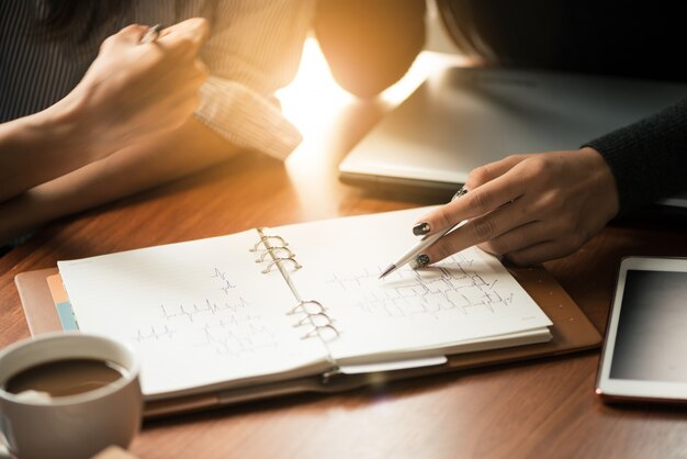 Processus de travail en équipe. Les jeunes chefs d'entreprise travaillent avec un nouveau projet de démarrage. Labtop sur la table en bois, clavier de saisie, message textuel, analyse les plans graphiques. Reflet.