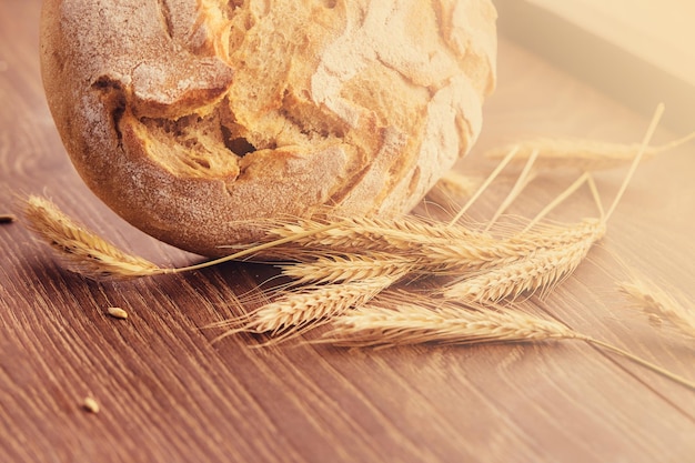 Photo gratuite produit de boulangerie isolé sur un fond en bois. pain frais et épillets de blé.