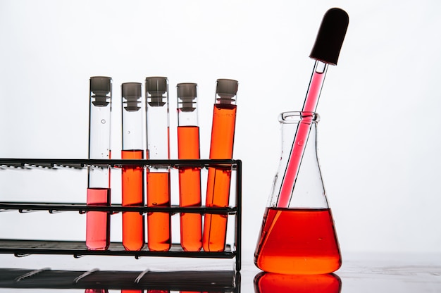 Produits chimiques orange dans un tube de verre scientifique disposé sur une étagère
