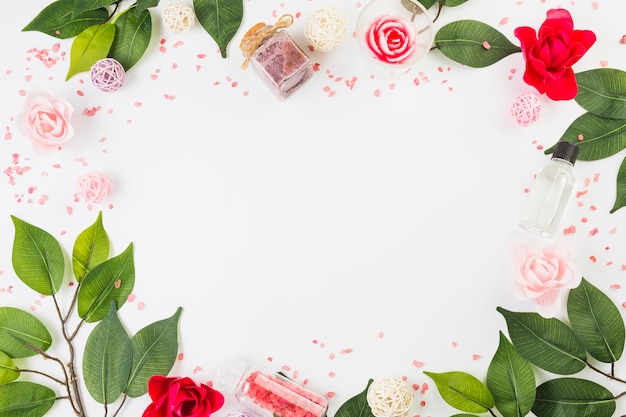 Produits cosmétiques et feuilles formant un cadre sur une surface blanche